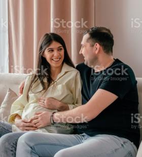 Mujer embarazada y hombre sentados en un sofá.