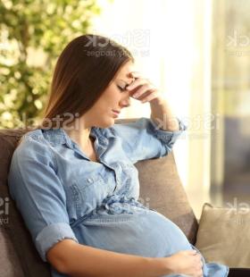 Mujer embarazada sentada en un sofá, no se siente bien.