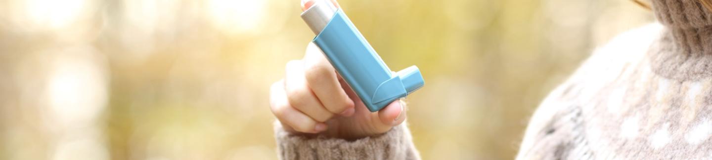 Woman holding asthma inhaler ready to use