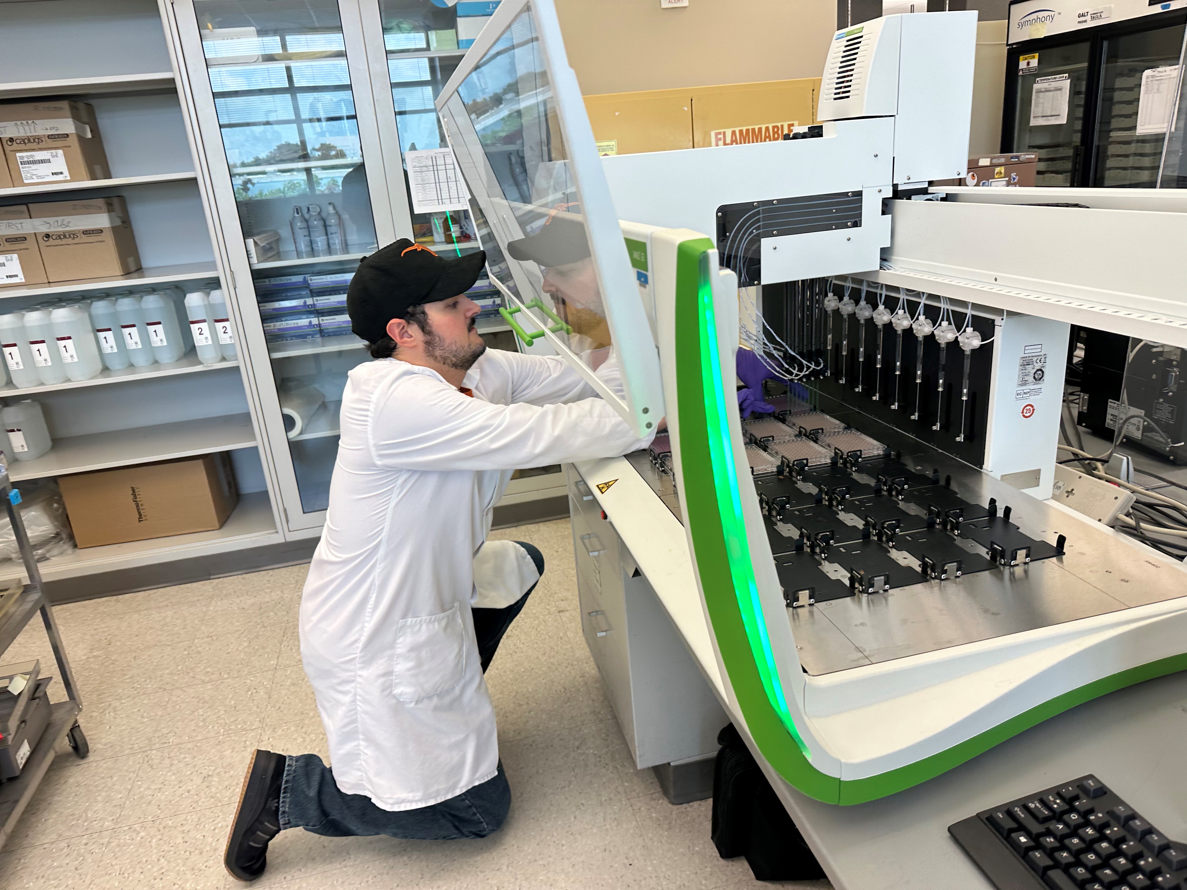 Lab technician kneeling in front of instrument 