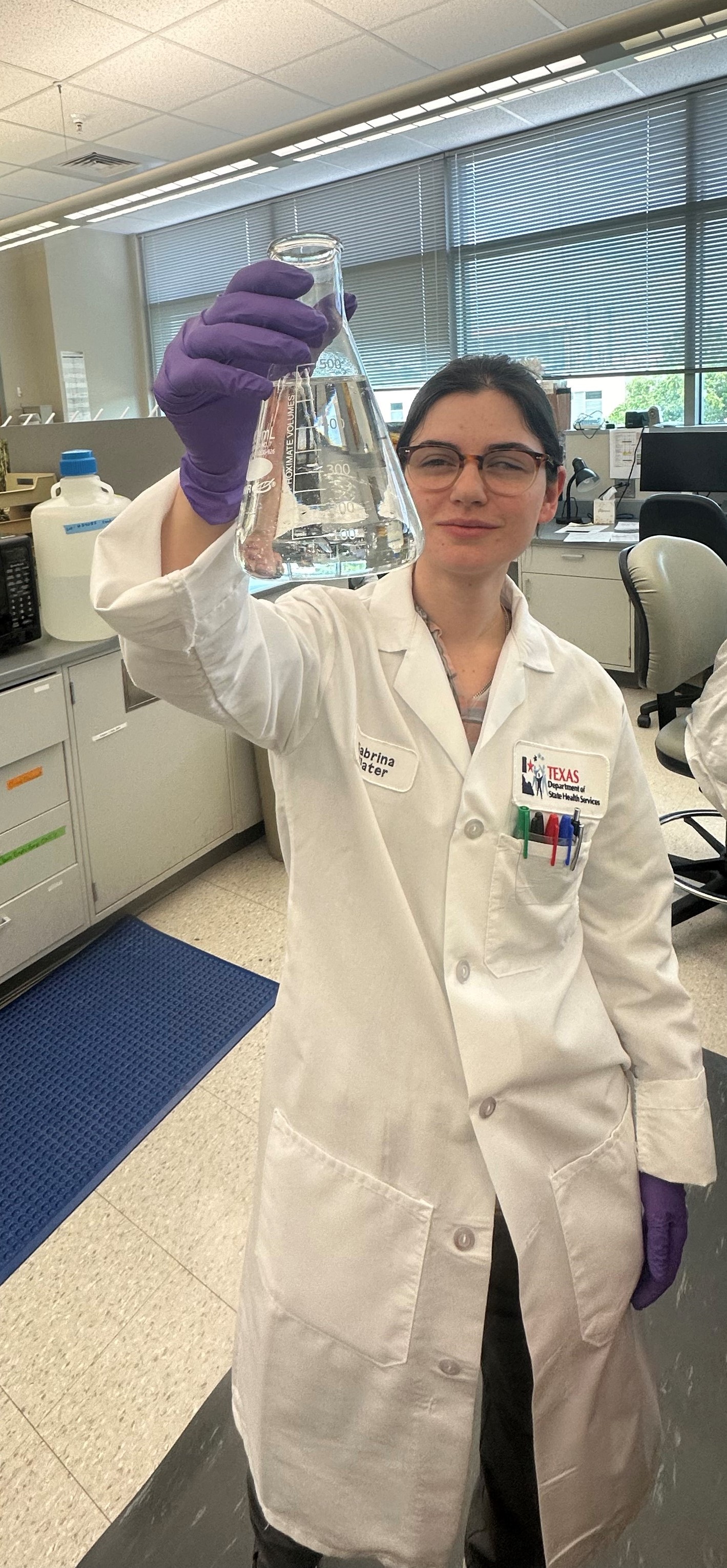 Lab Technician holding a beaker. 