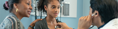 A girl and her mother speak to a doctor.