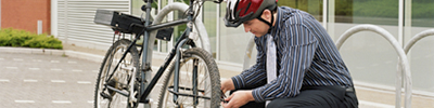 A man in a suit and helmet locks up his bicycle.